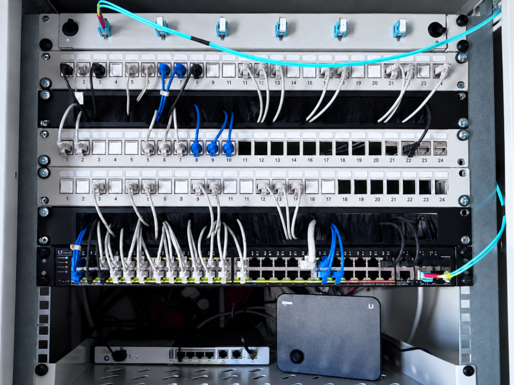 Detailaufnahme eines sauber verkabelten Netzwerkschranks mit Patchfeld und Switch in einem Orthopädiezentrum in Wien